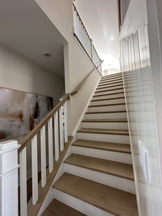 there is a staircase leading up to the second floor with white railings and wood handrails