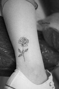 a small rose tattoo on the ankle is shown in this black and white photo,