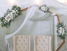 two chairs with flowers on them are sitting in front of a white drape covered wall