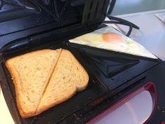 an open toaster with two slices of bread and eggs in it sitting on a counter