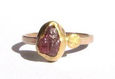 Natural rough dark pink Tourmaline (about 8 x 6 mm), Is wrapped in 22k solid yellow gold with a 22k gold stamped disc on one side. It all rests on a flat 9k solid yellow gold band, about 1.5 mm wide and 1 mm thick. Matte finish. This ring size is a 6. Can be enlarged a bit. READY TO SHIP! In a gift box. Brown 14k Gold Fine Jewelry Ring, Handmade Gold Tourmaline Ring, Handmade Tourmaline Gold Ring, Handmade Yellow Gold Ruby Ring, Fine Jewelry, Red 14k Gold-filled Gemstone Jewelry, Stackable Engagement Ring, Rough Stone Ring, Gold Rings Stackable, Tourmaline Ring