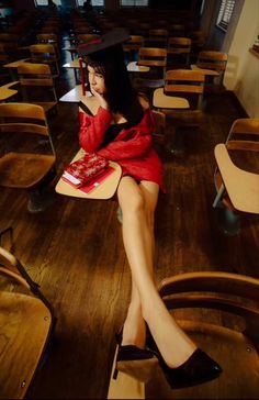 a woman sitting on top of a wooden table in a room filled with desks