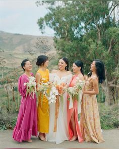 a group of women standing next to each other holding bouquets in their hands and laughing