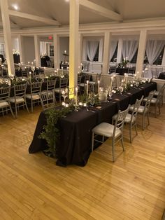 a room filled with lots of tables covered in black table cloths and white chairs