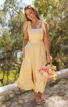 a woman in a yellow dress holding flowers