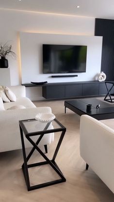 a living room filled with white furniture and a flat screen tv mounted on the wall