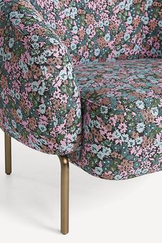 an upholstered chair with pink and blue flowers on the back, viewed from the side