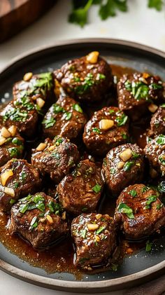 a plate full of meatballs covered in sauce and garnished with parsley