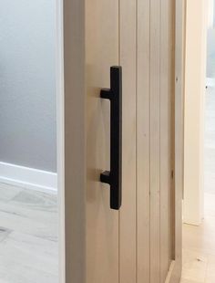 an open door with a black handle on the front and side of it in a white room