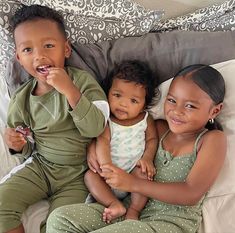 two young children sitting on top of a bed next to each other, one holding a toothbrush