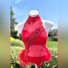 a red dress on display in front of some bushes