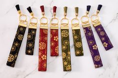 six keychains with different designs on them sitting next to each other in front of a marble surface