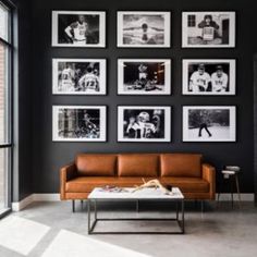 a living room with black walls and pictures on the wall, including a leather couch