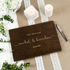 personalized wooden guest book with lace trim and candles on table next to white flowers