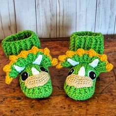 a pair of crocheted slippers with a green and yellow cow's head