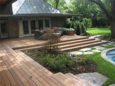 a wooden deck next to a swimming pool in a backyard with steps leading up to it