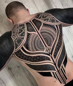 a man's back with an intricate tattoo design on his upper and lower half