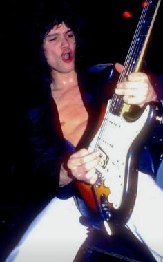 a shirtless man holding an electric guitar