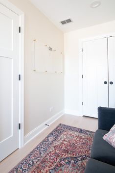 a living room with a couch and rug in front of two doors on the wall