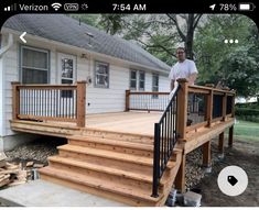 a man standing on top of a wooden deck next to a white house and trees