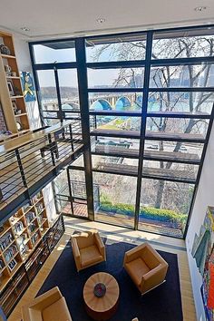 a living room filled with lots of furniture next to a large window covered in bookshelves