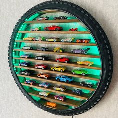 a wall mounted toy car display in a tire rim with shelves for cars on it