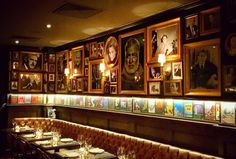 a restaurant with many framed pictures on the wall and long tables in front of it