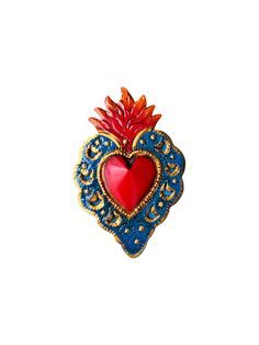 a red heart shaped brooch sitting on top of a white surface with gold trim