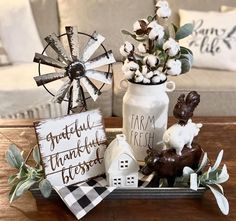 a wooden table topped with a vase filled with flowers and figurines next to a sign