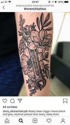 a person with a tattoo on their arm that has flowers and a key in it