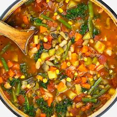 a pot full of vegetable soup with a wooden spoon