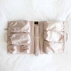 an open suitcase sitting on top of a white sheet covered bed with ruffles