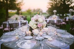 the table is set with silverware and white flowers in vases, candles and plates