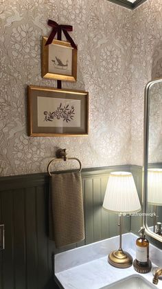 a bathroom sink sitting under a mirror next to a wall mounted faucet and lamp