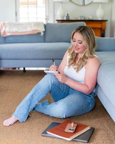 a woman is sitting on the floor with her notebook and pen in front of her