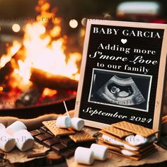 a sign with marshmallows on it sitting in front of a fire