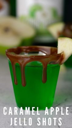 caramel apple jello shots with chocolate drizzled on the rim and apples in the background