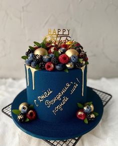 a blue birthday cake with berries, raspberries and chocolate drizzles