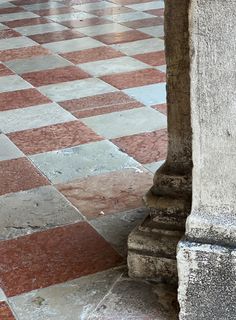 an old stone pillar with a checkerboard pattern on the floor next to it