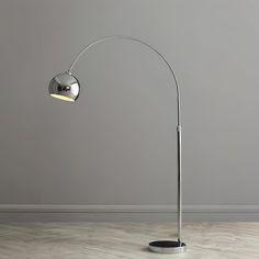 a lamp that is on top of a wooden floor in front of a gray wall