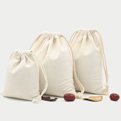 three bags filled with different types of food on a white surface, one is empty and the other has two small pieces of fruit in it