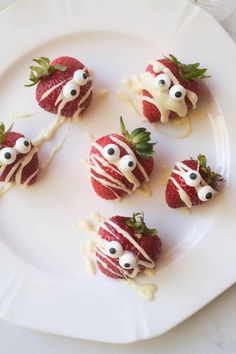 strawberries with googly eyes and white icing on a plate