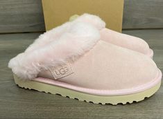 a pair of pink slippers sitting on top of a wooden floor next to a cardboard box