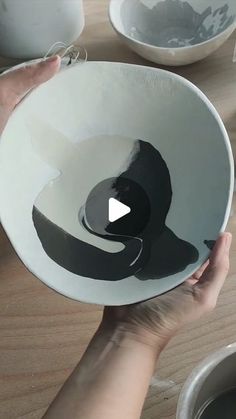 a person holding a white bowl with black designs on it