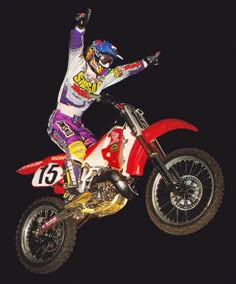 a man riding on the back of a red dirt bike in the air at night