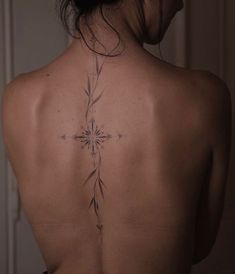 the back of a woman's neck with a cross tattoo on her left side