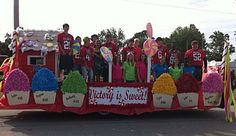 a group of people riding on the back of a truck decorated with cupcakes