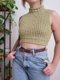 a woman in jeans and a crop top is posing for the camera with her hands on her hips