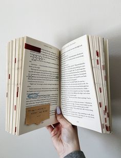 a person is holding an open book in their left hand and pointing it at the page