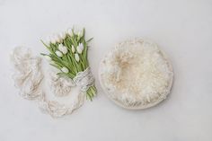 tulips and lace on a white surface next to a bowl with flowers in it